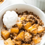 A bowl of healthy apple crumble with a scoop of vanilla ice cream on top.