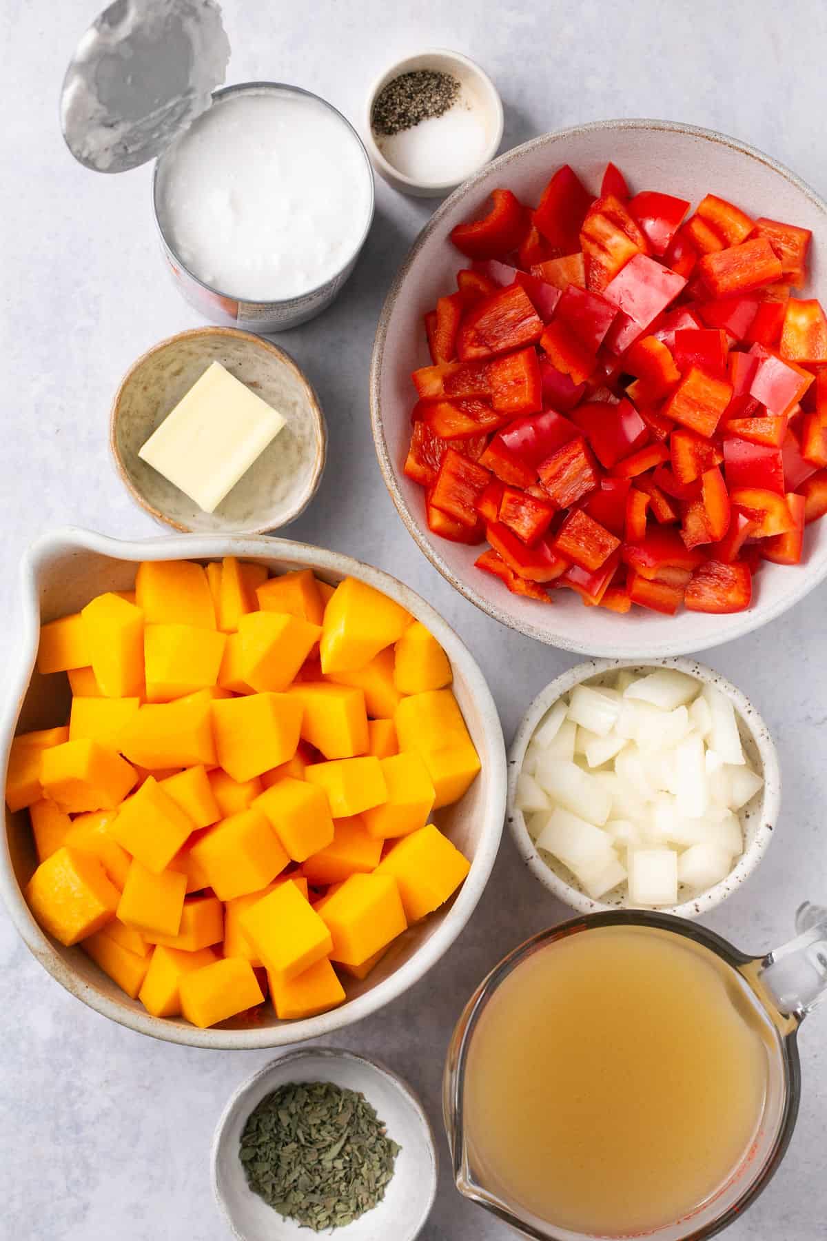 The ingredients needed to make a butternut squash and red pepper soup separated into small bowls. 