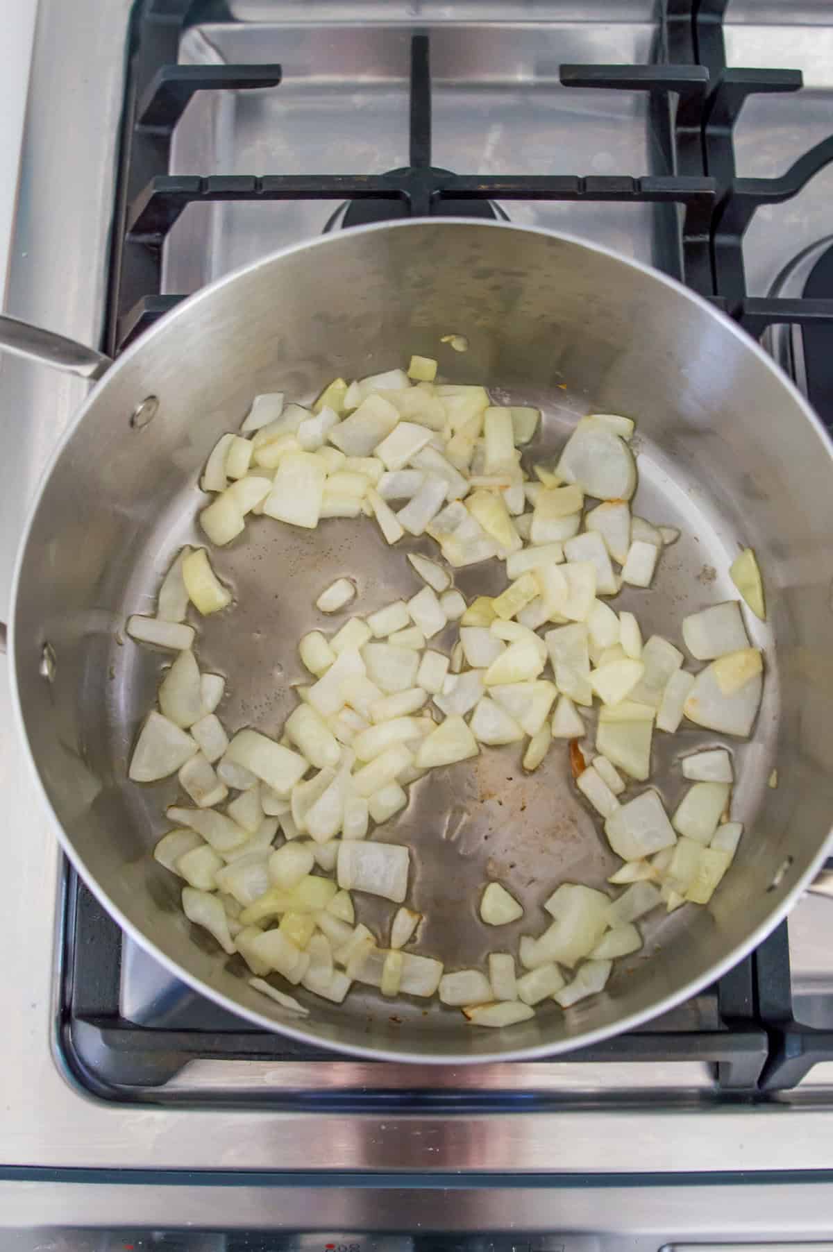 Chopped onions cooking in a pot on the stovetop.