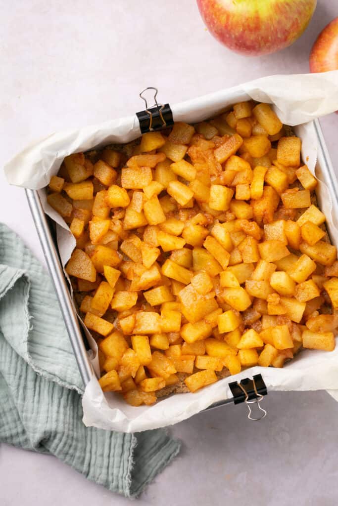 A square baking pan with cooked apples in it.