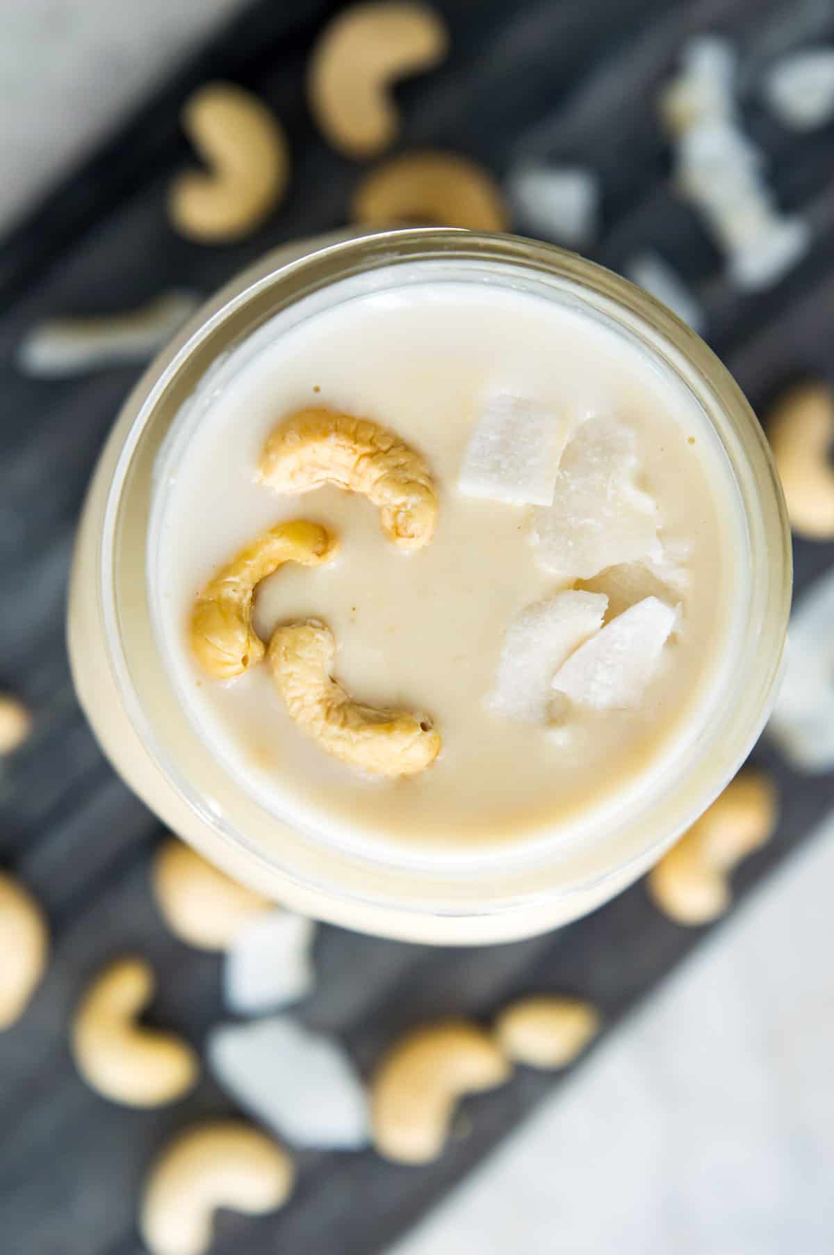 A jar of cashew coconut butter with raw cashews on top.