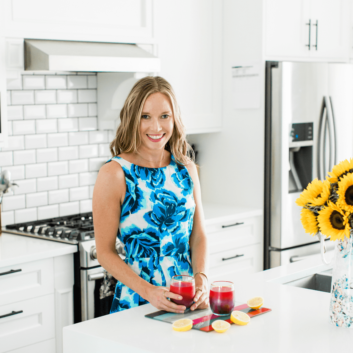 A photo of Dr. Erin Carter wearing a floral dress in her kitchen.