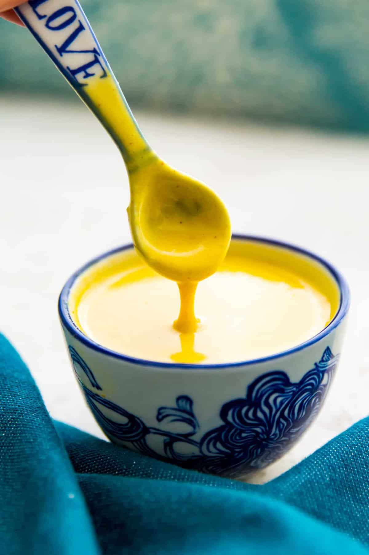 A bowl of honey mustard sauce with a spoon in it.