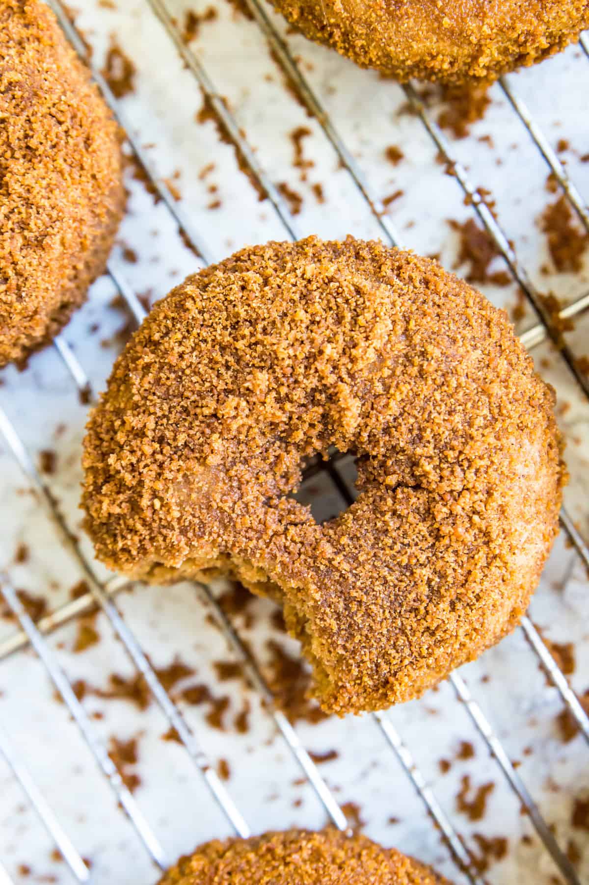 Vegan donuts coated in cinnamon sugar on a baking rack.