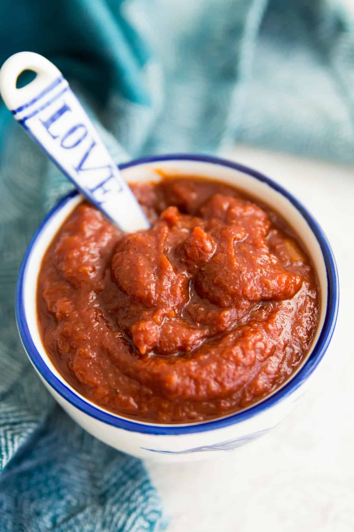 A bowl of barbecue sauce with a spoon in it.