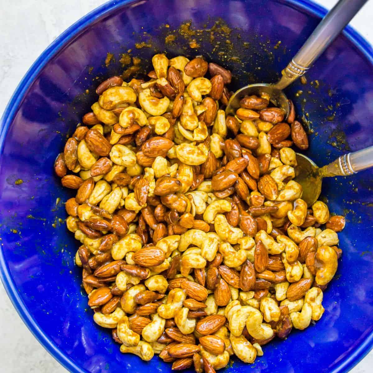 Almonds and cashews in a bowl coated in a curry spice.