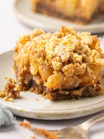 A healthy apple crumble bar on a plate with a bite taken out of it and a fork beside it.