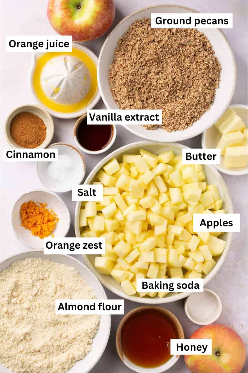 Different ingredients in bowls including almond flour, ground pecans, chopped apples, honey, vanilla extract and orange juice.