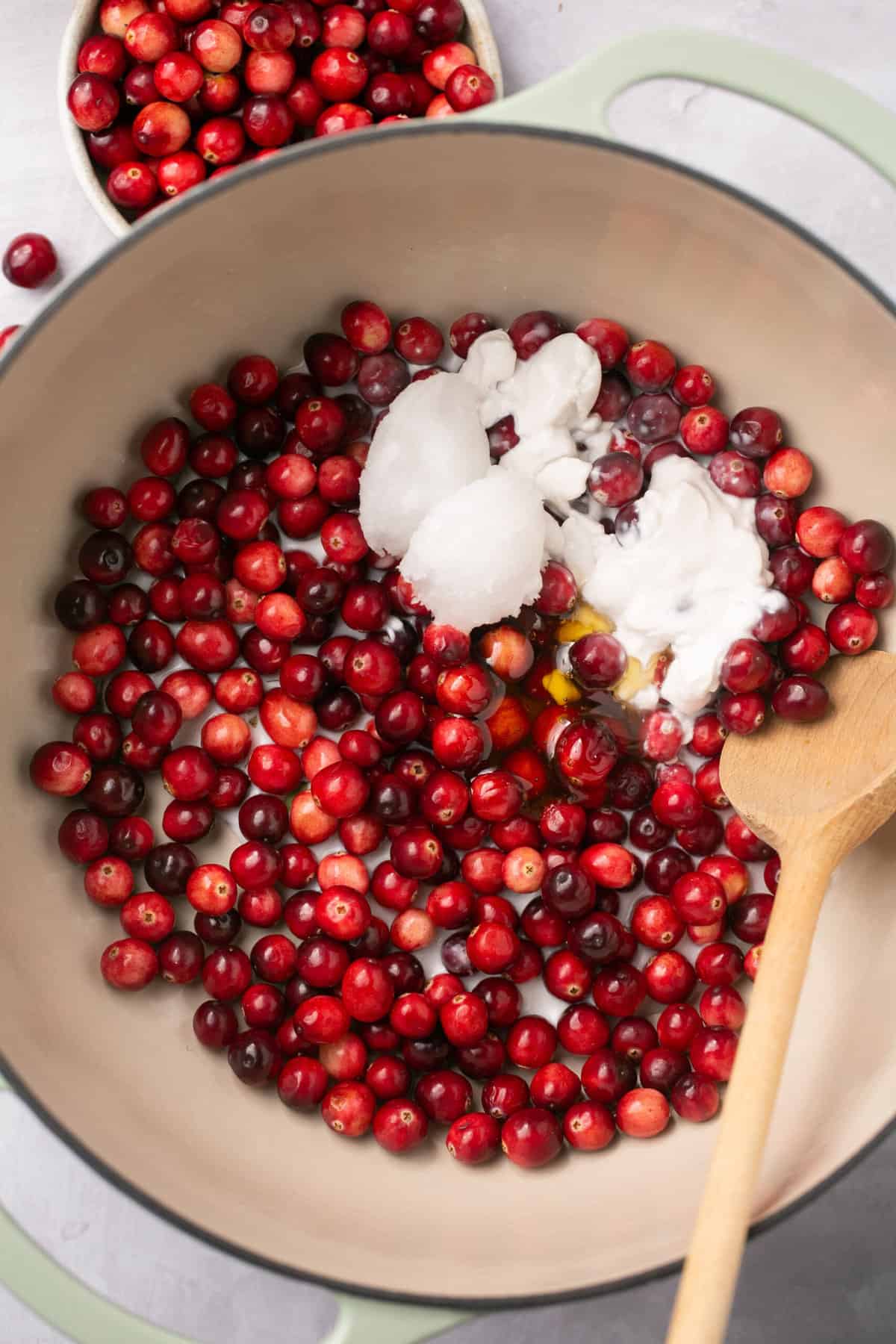 A pot filled with fresh cranberries, coconut oil and honey. 