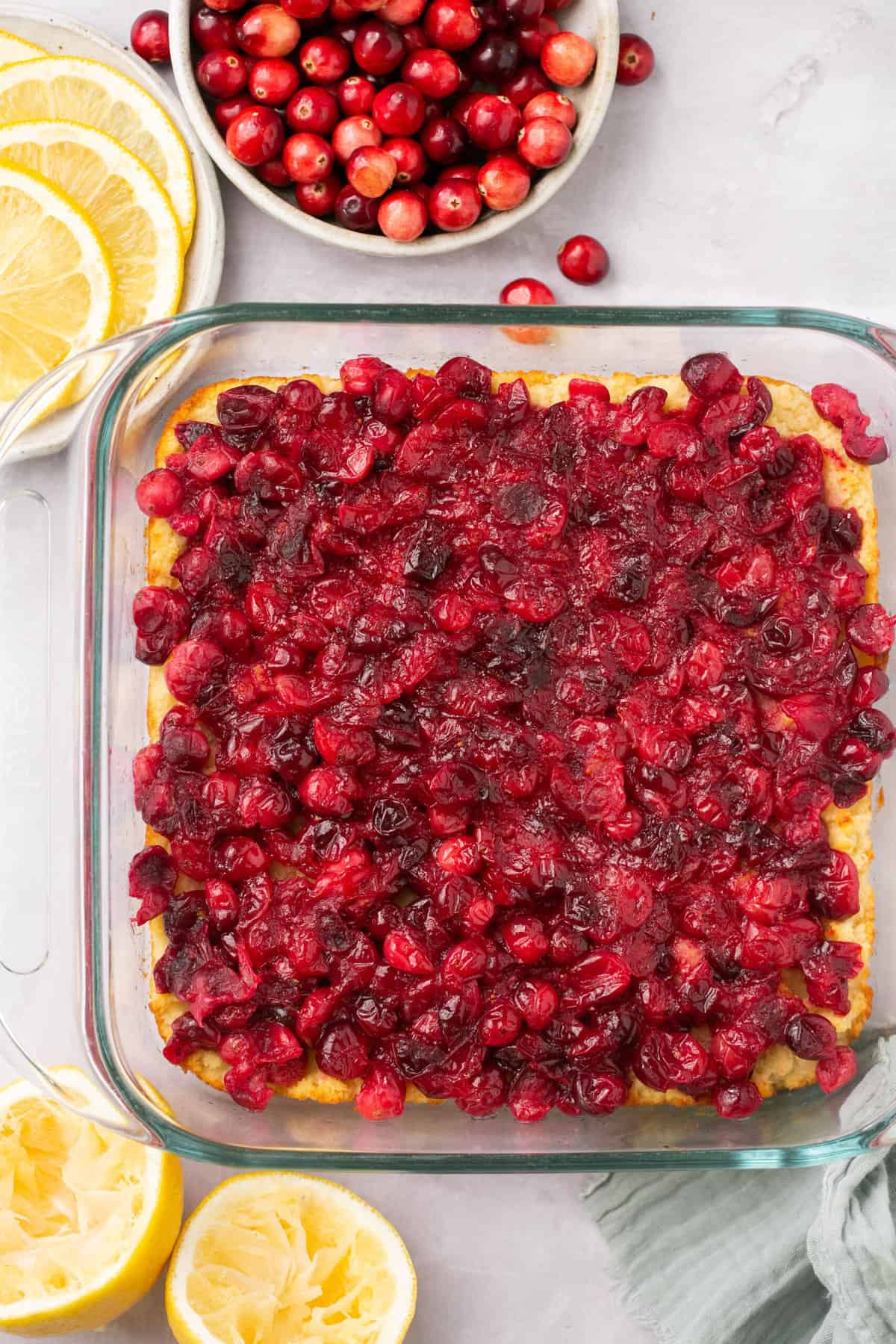 A lemon square with cooked cranberries on top in a baking dish. 