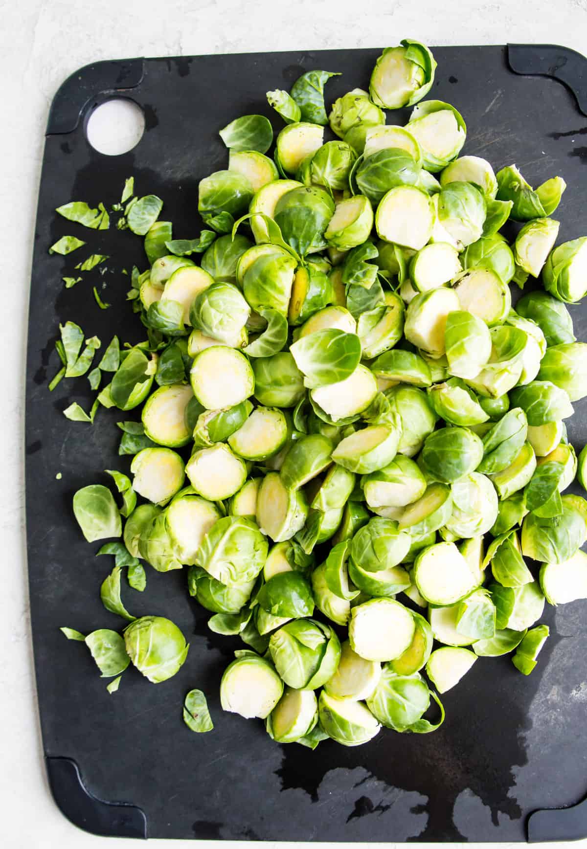 Chopped Brussels sprouts on a black cutting board. 