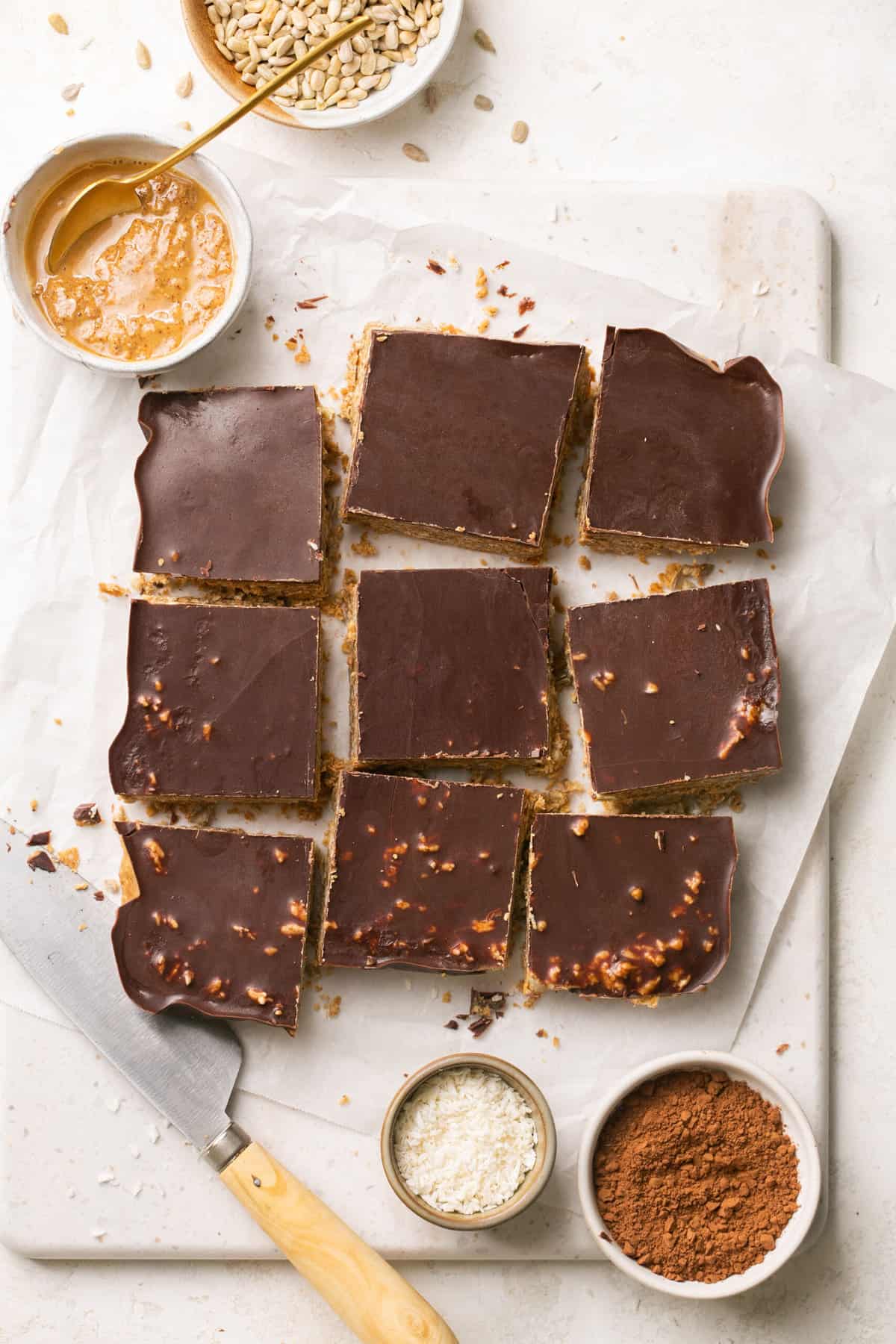 Chocolate almond butter bars cut into pieces with a bowl of almond butter beside them. 
