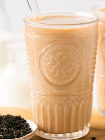 Two glasses of Hokkaido milk tea with glass straws in them.