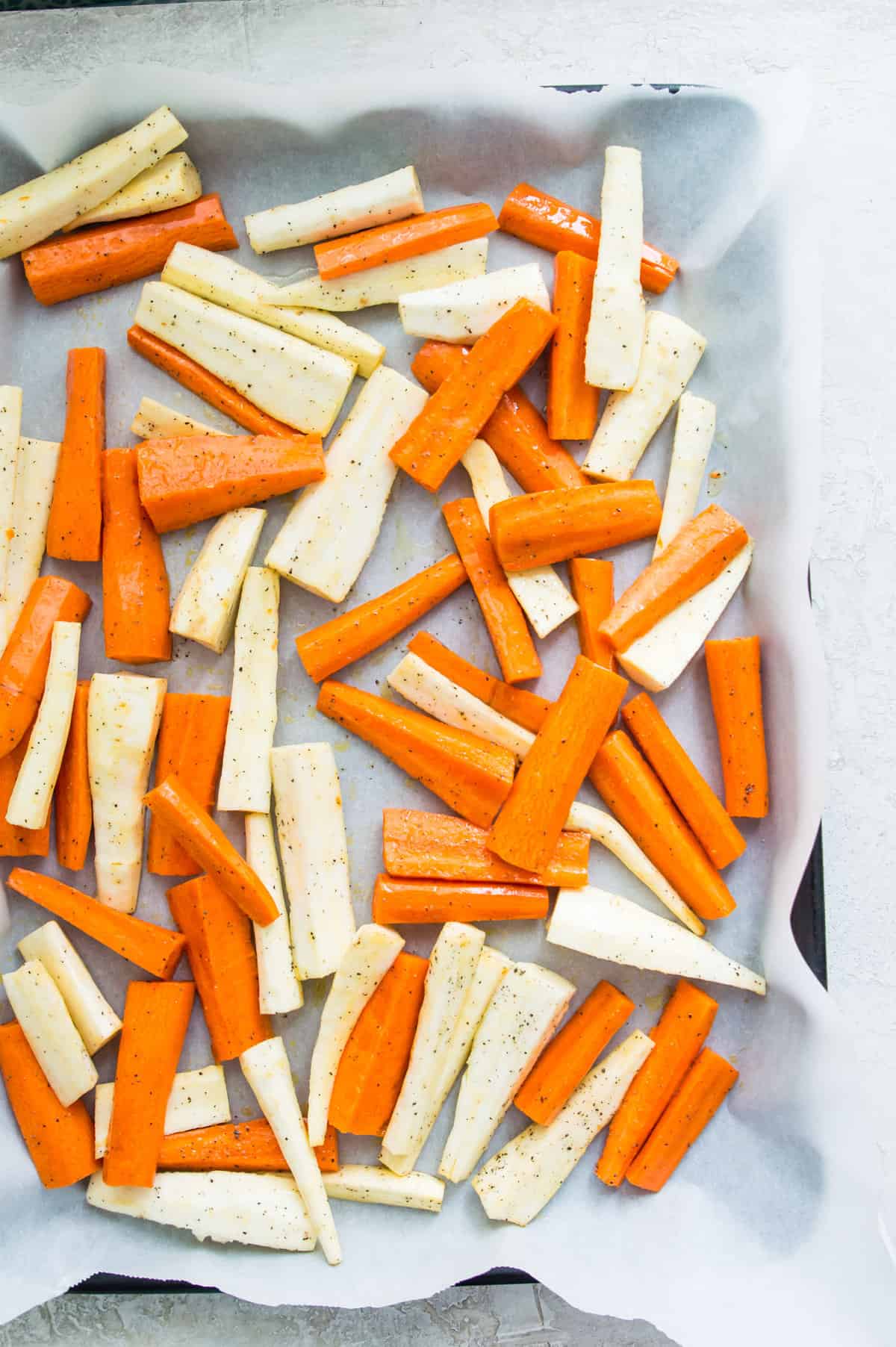 Cut carrots and parsnips on a piece of parchment paper on a baking sheet. 