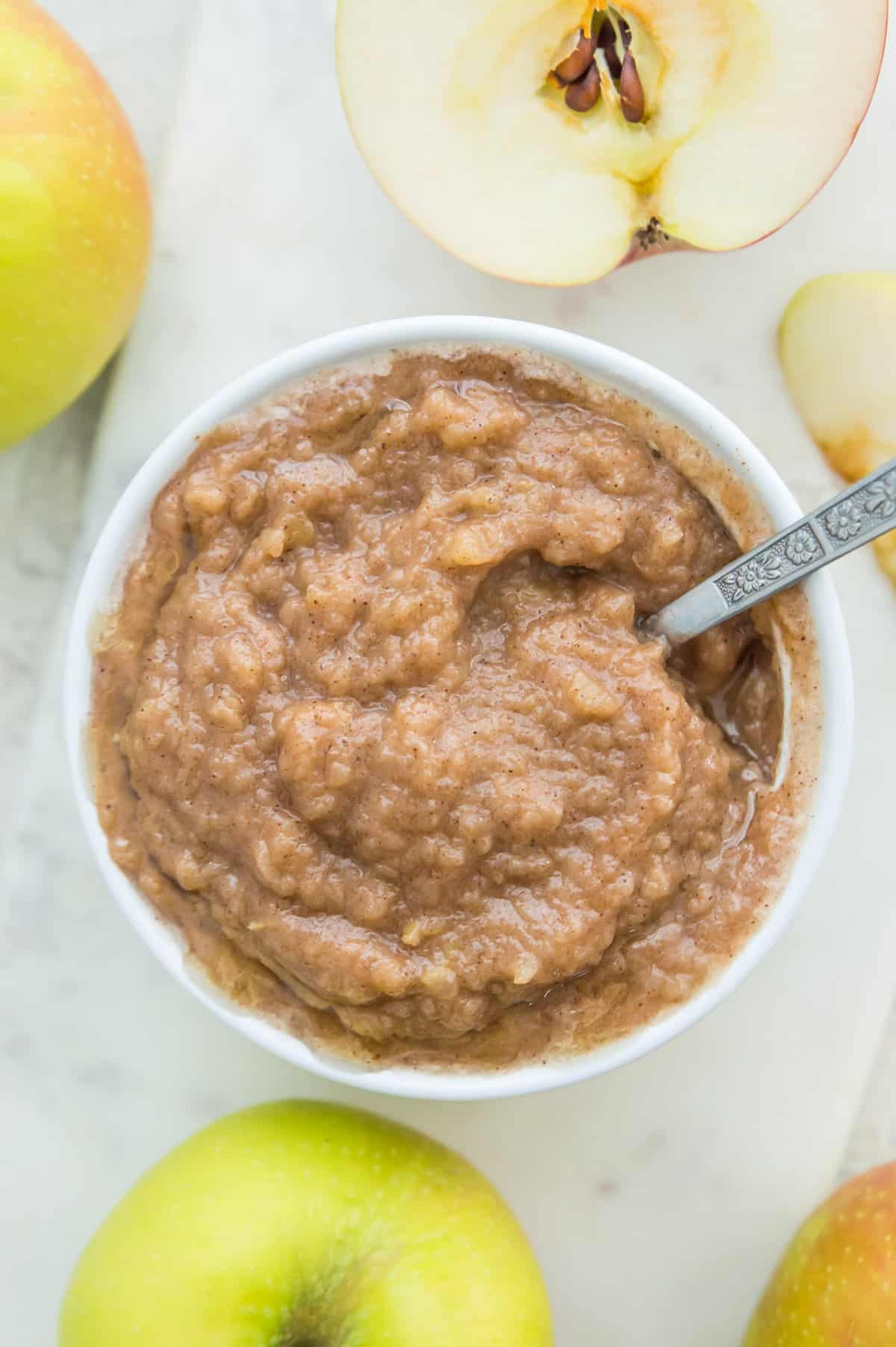 A bowl of homemade sugar free applesauce with a spoon in it.