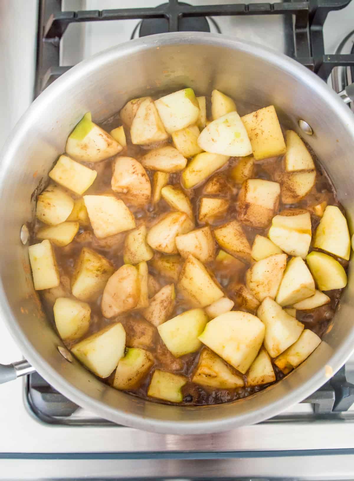 Chopped and peel apples boiling in a pot of water on the stovetop.