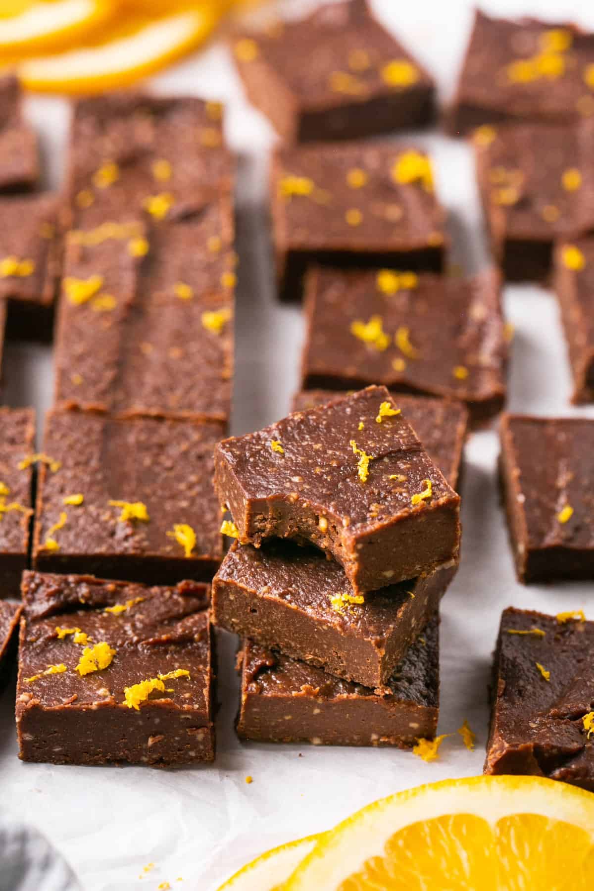 Pieces of orange chocolate fudge stacked on each other and once pieces has a bite out of it.