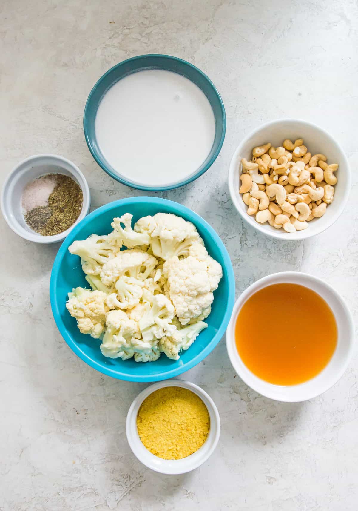 The ingredients needed to make a cauliflower Alfredo sauce, separated into bowls. 