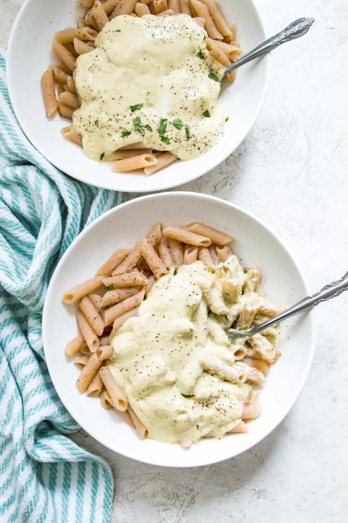 Two bowls of pasta with cauliflower Alfredo sauce on them. 