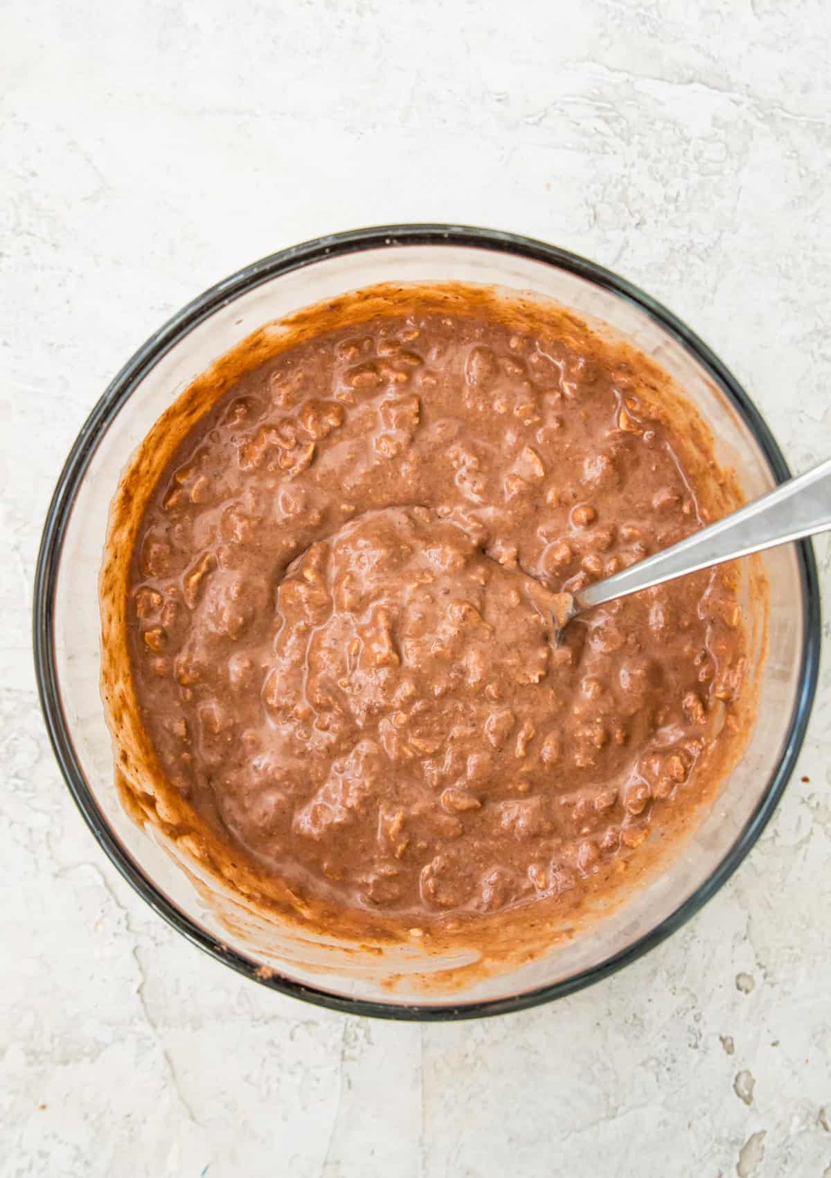 A bowl with chocolate oatmeal in it and a spoon. 