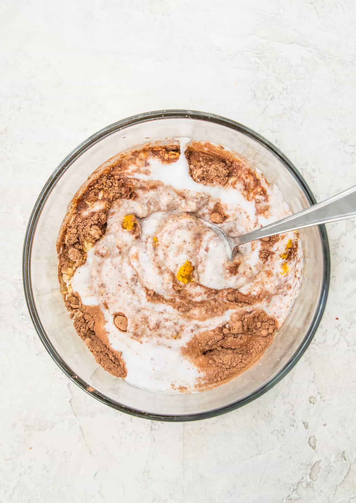 A bowl with cocoa powder, coconut milk and oats in it. 