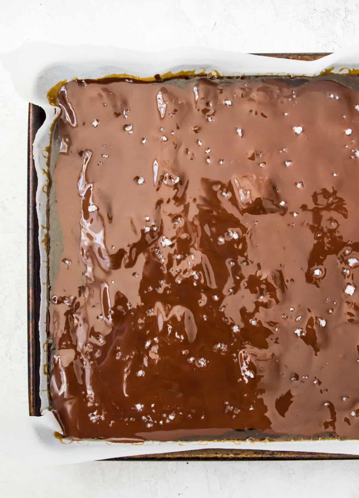 Dark chocolate spread out on a baking sheet lined with parchment paper.
