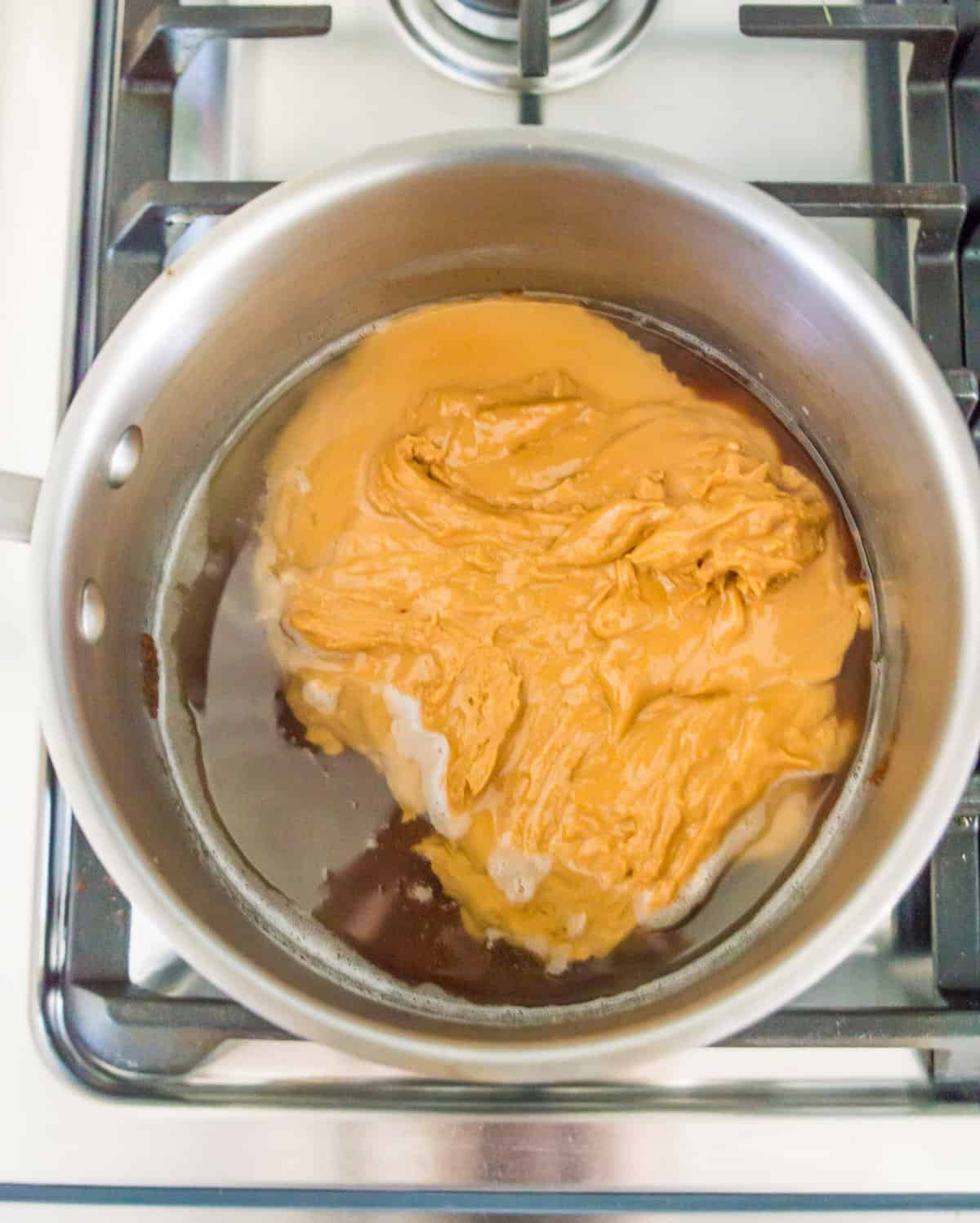 Peanut butter, coconut oil and maple syrup in a pot on the stovetop.