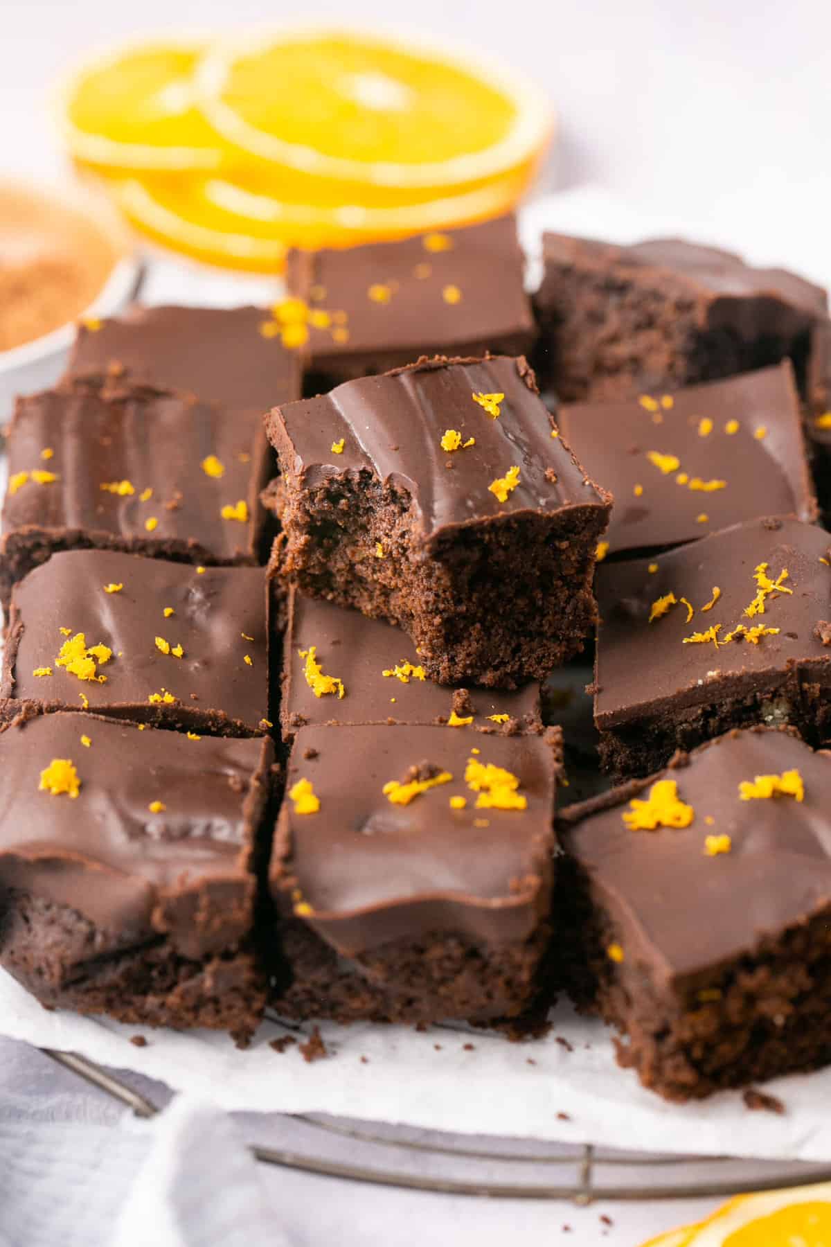 A stack of orange chocolate brownies garnished with orange zest. 