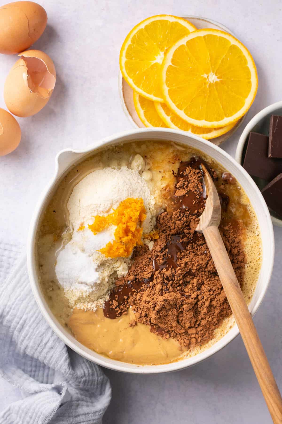 Orange chocolate brownie batter in a mixing bowl with a spoon in it. 