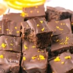 A stack of orange chocolate brownies, one with a bite out of it.