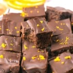 A stack of orange chocolate brownies, one with a bite out of it.