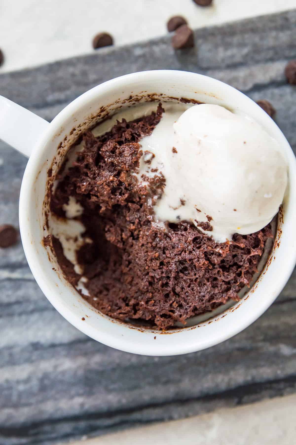 A chocolate mug cake topped with vanilla ice cream.