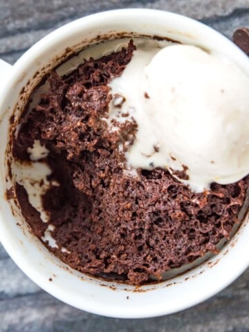 A mug filled with a 3 ingredient mug cake topped with vanilla ice cream.