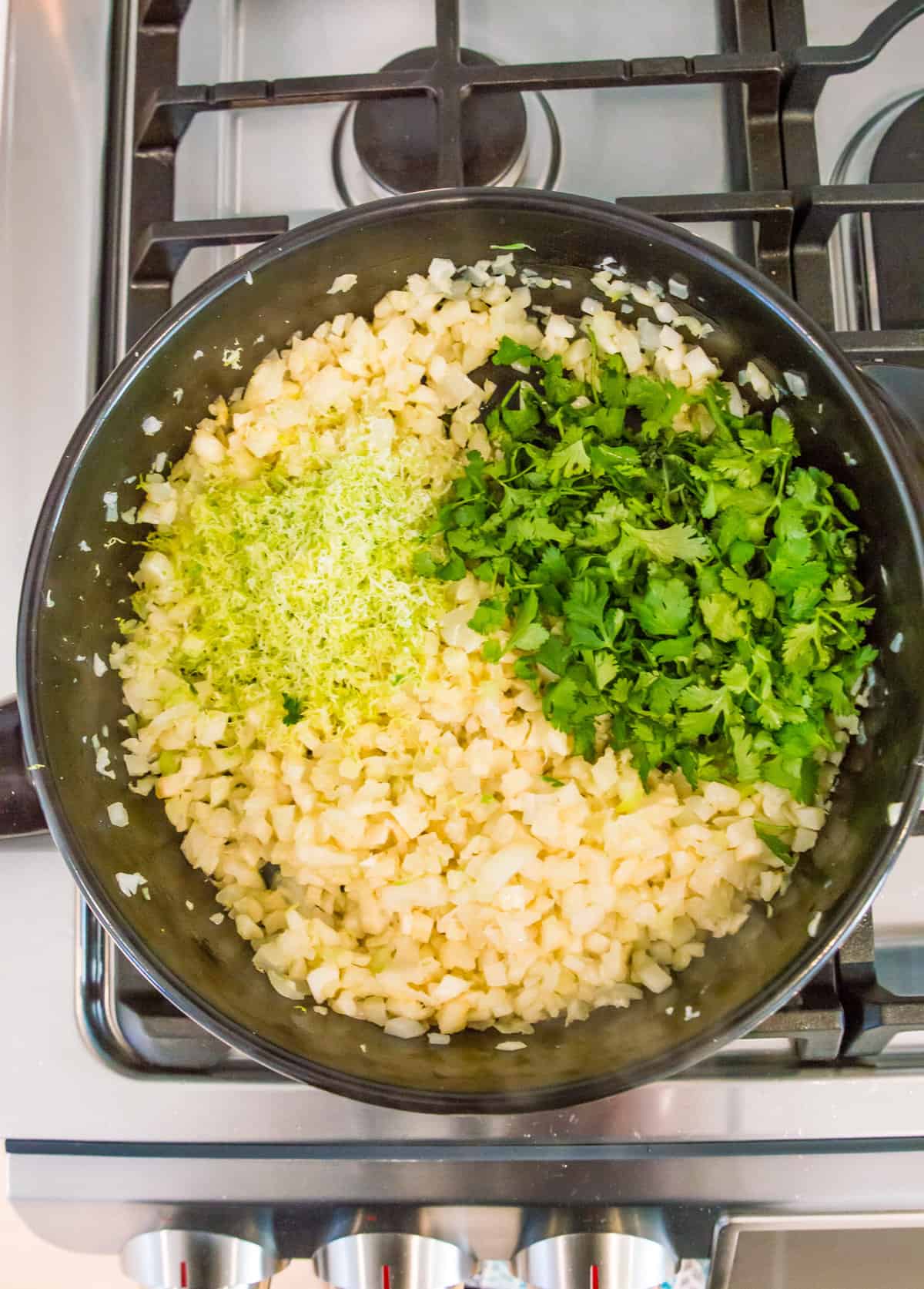 A pan full of riced cauliflower with fresh cilantro and lime zest on top.