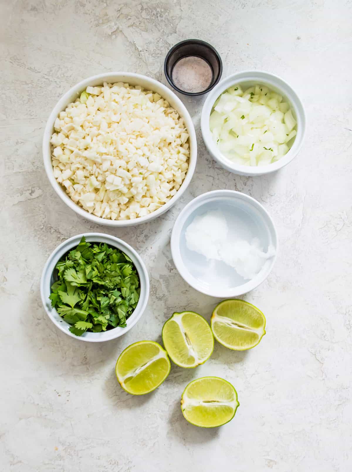 The ingredients needed to make cilantro lime cauliflower rice separated into bowls.