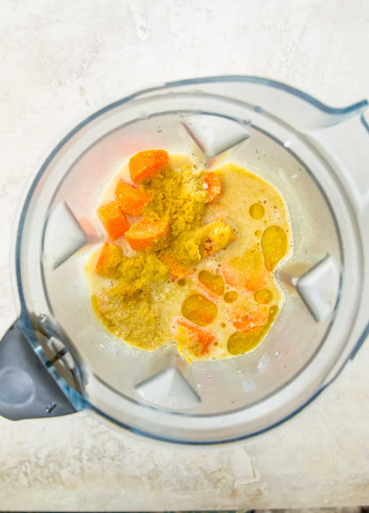 A blender with carrots, coconut milk and nutritional yeast in it. 
