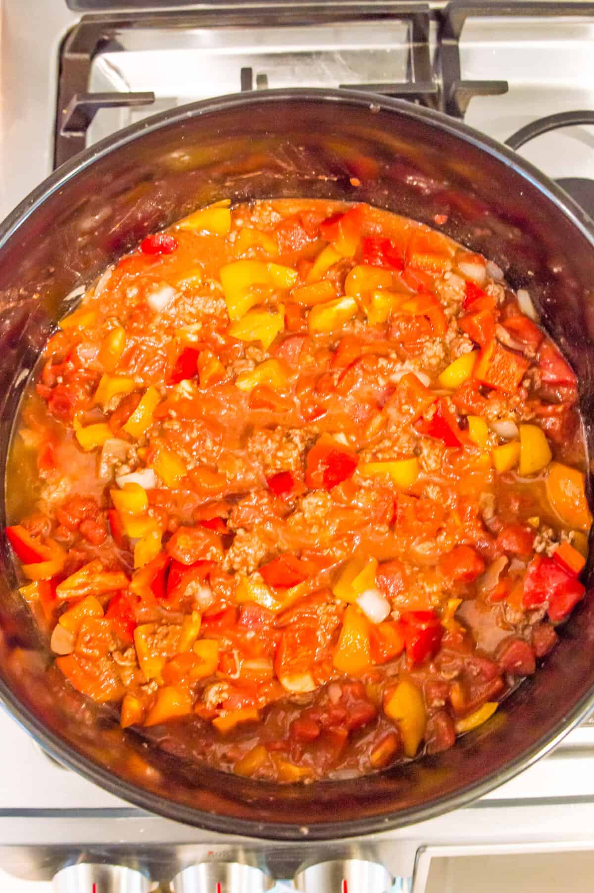 A large pot on the stovetop with a healthy chili in it.