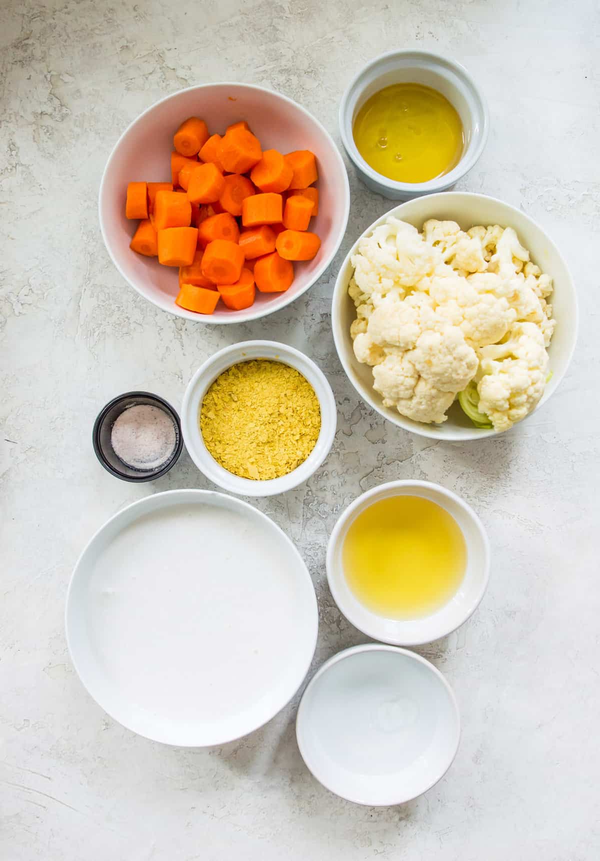 The ingredients needed to make vegan cheese sauce separated into bowls. 