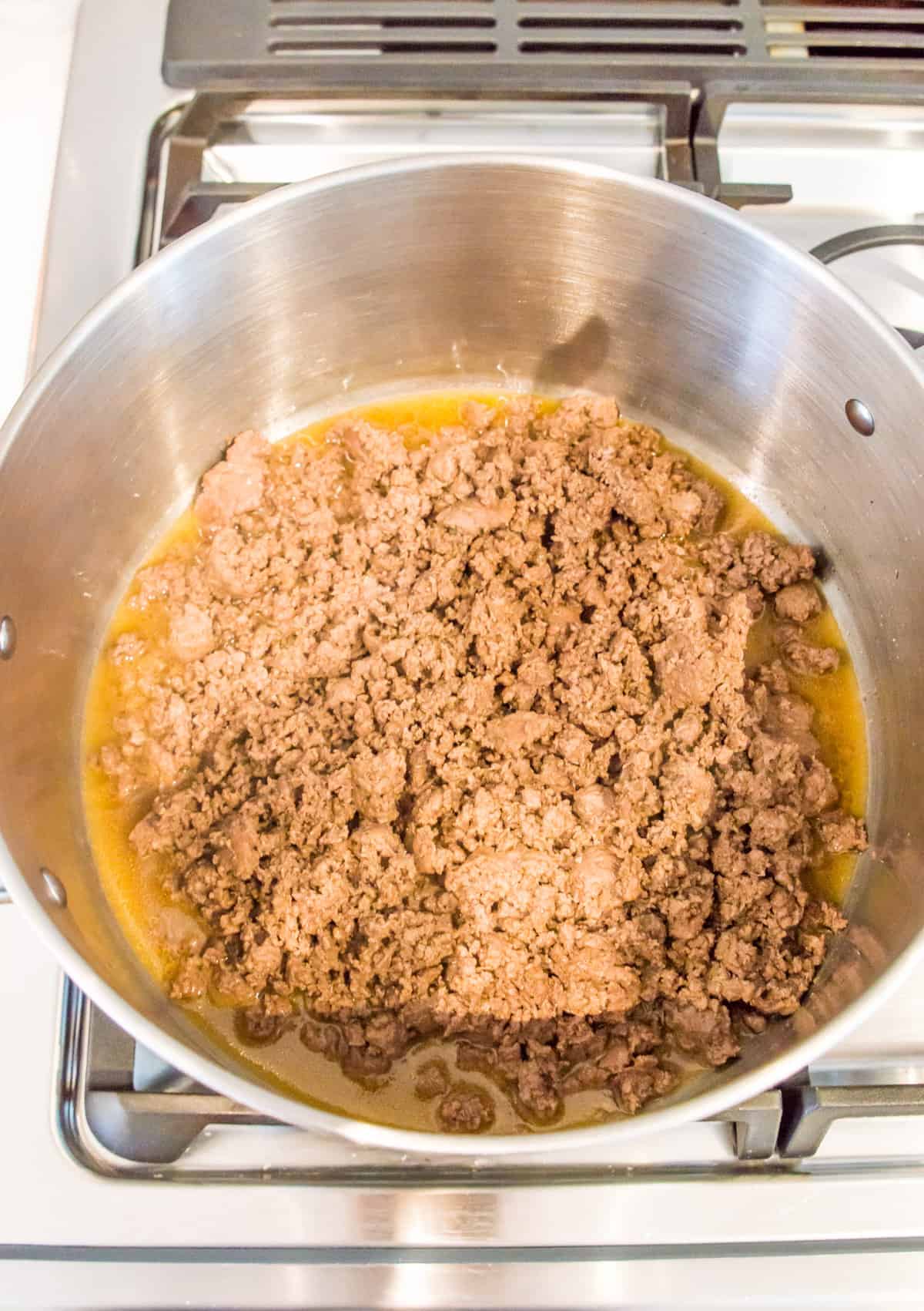 A pot full of cooked ground beef on the stovetop.