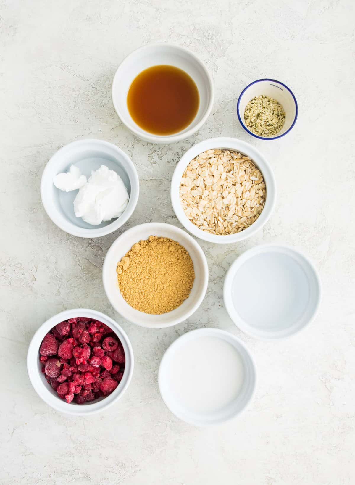 The ingredients needed to make cheesecake overnight oats separated into bowls. 