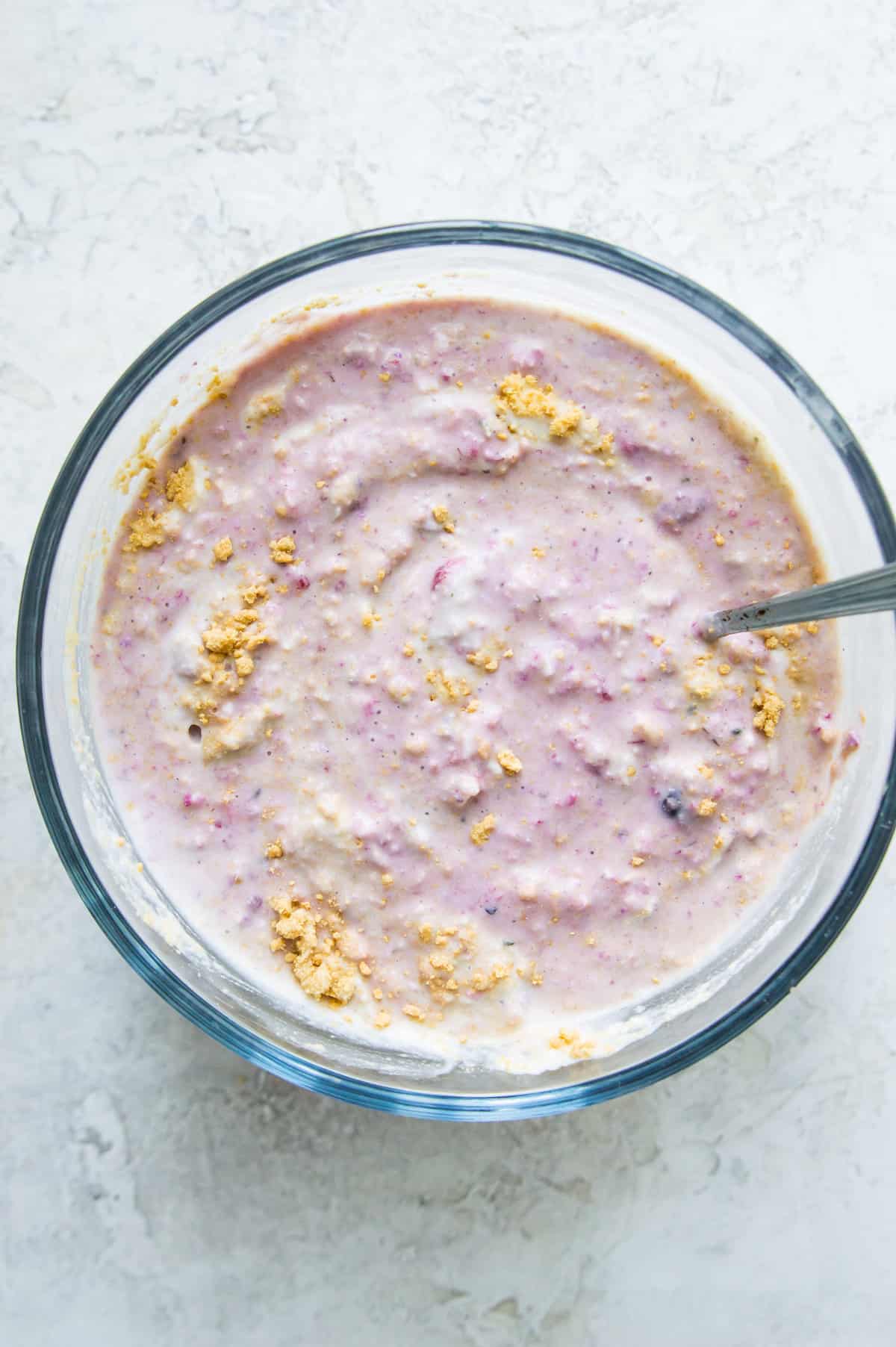 A bowl of overnight oats with graham cracker crumbs sprinkled on it and a spoon in it.