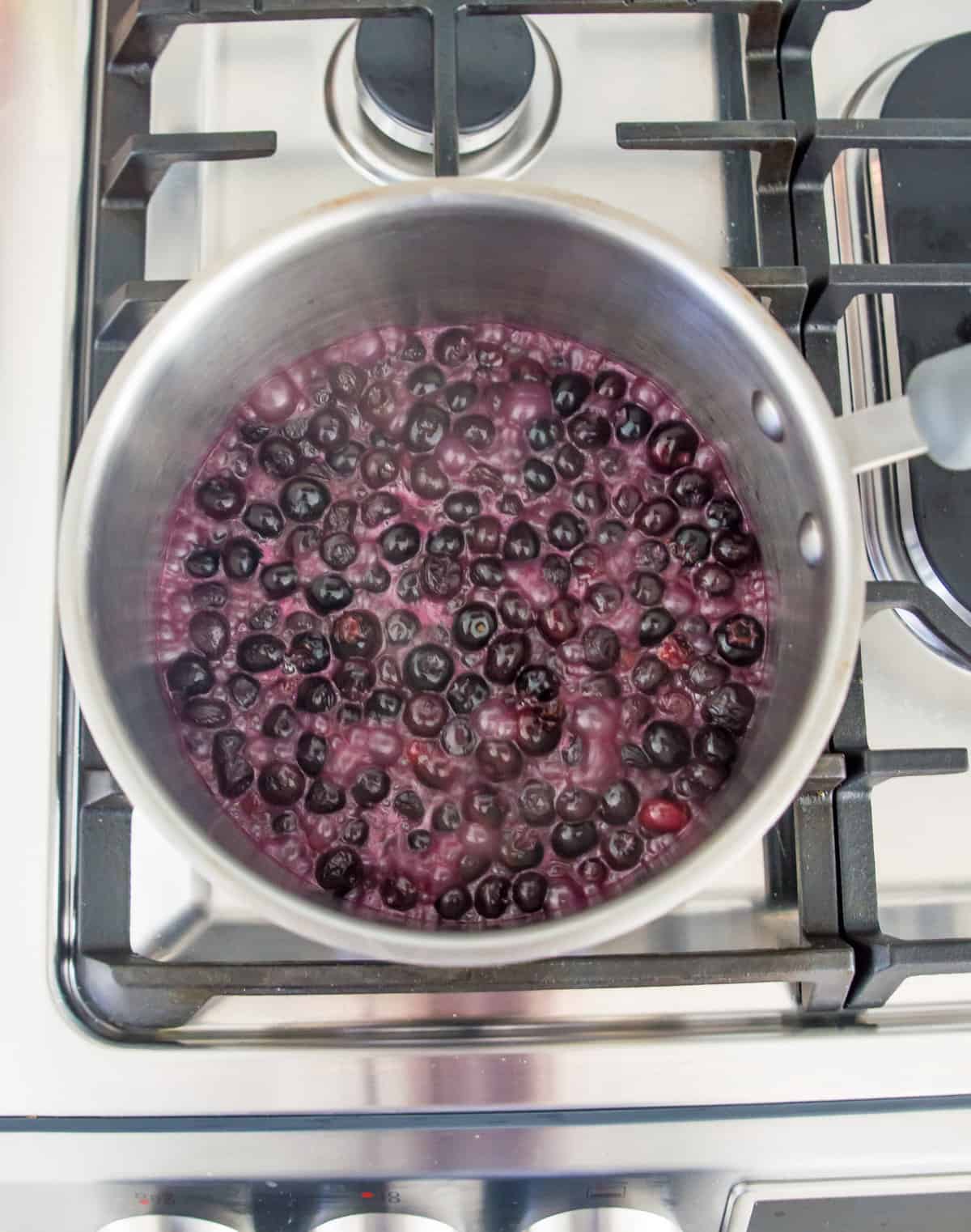 Blueberries and coconut milk boiling in a pot on the stovetop.