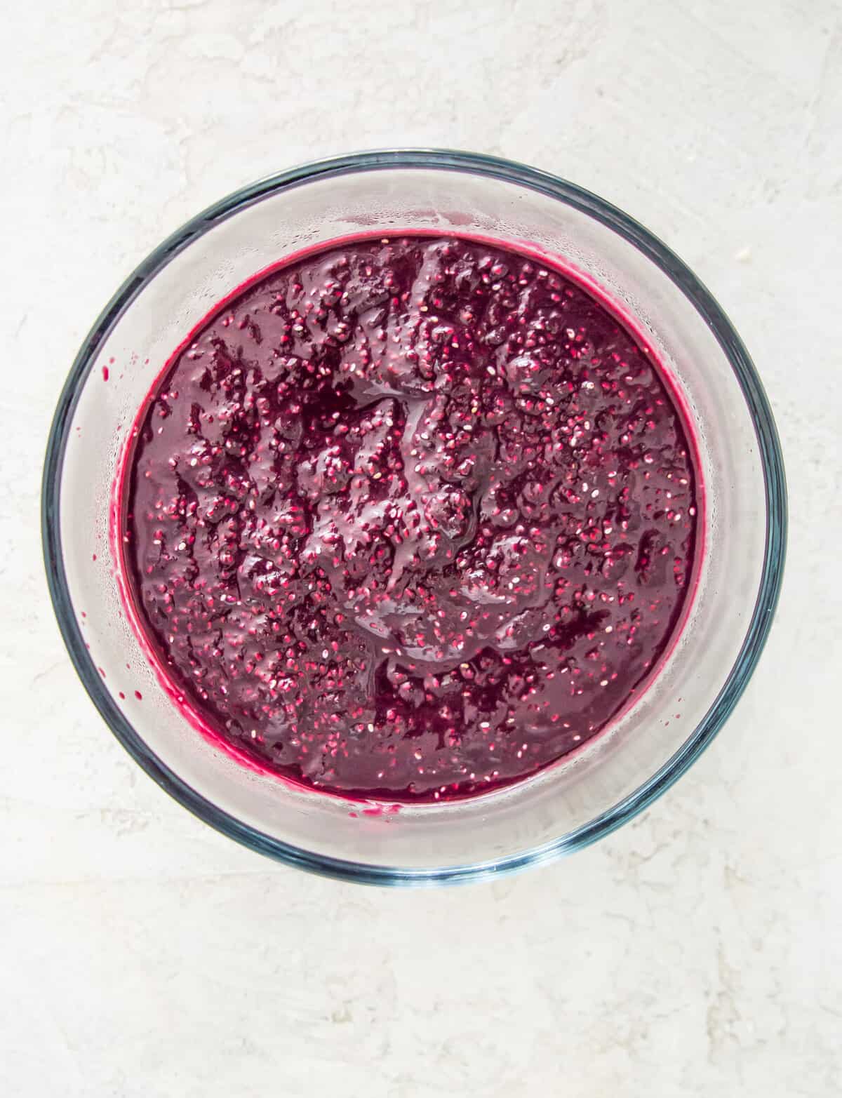 Blueberry chia seed jam in a clear bowl.