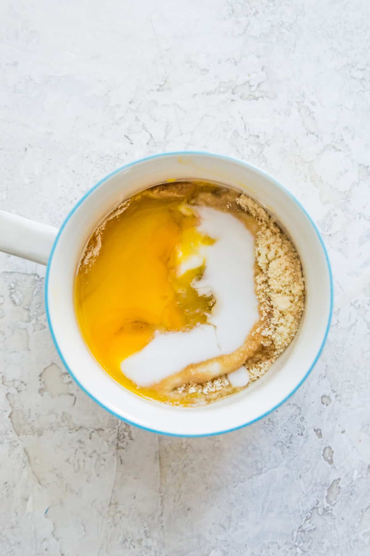 An egg, protein powder, maple syrup and almond flour in a mug.