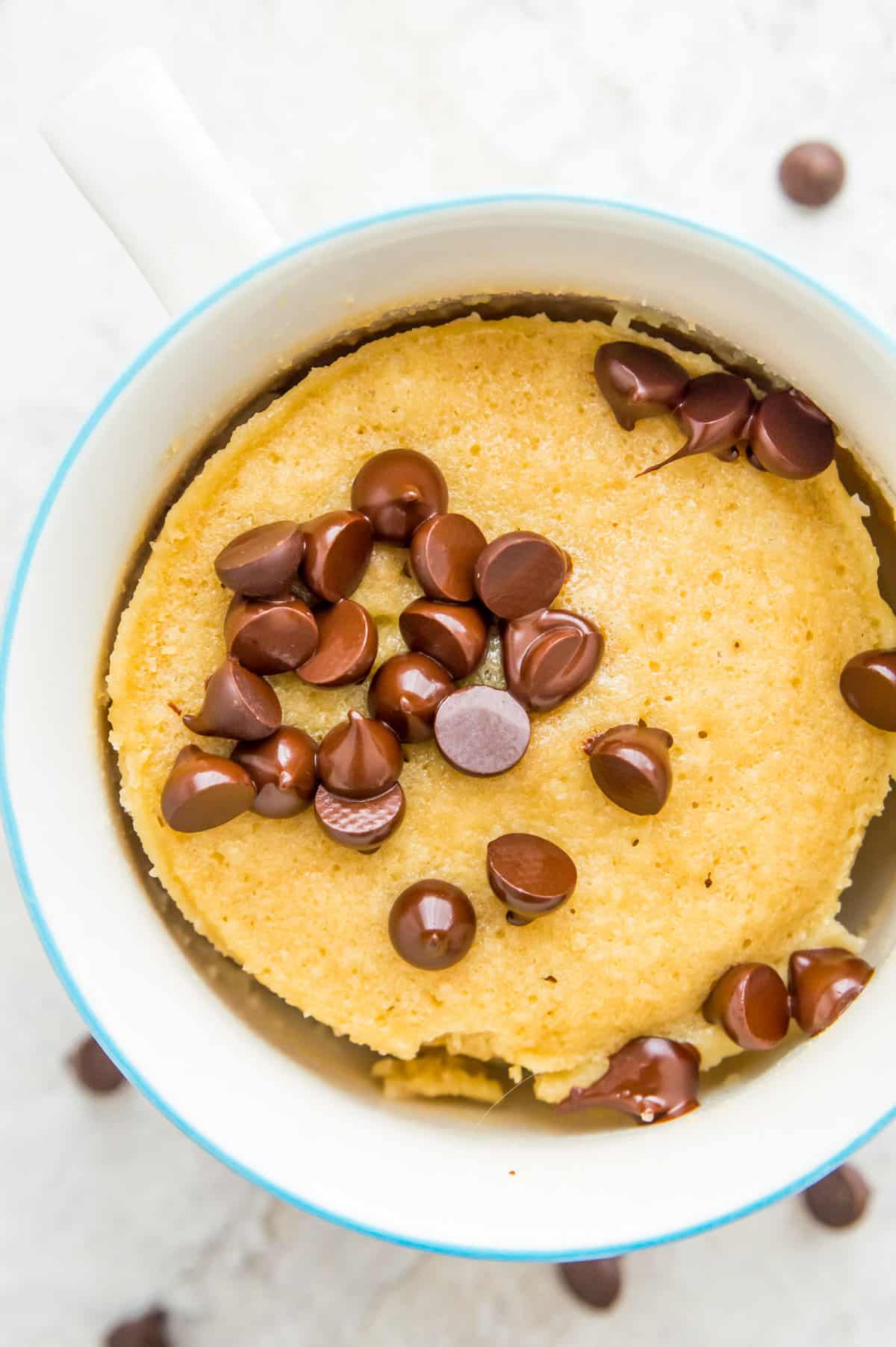 A mug of vanilla protein mug cake topped with chocolate chips. 