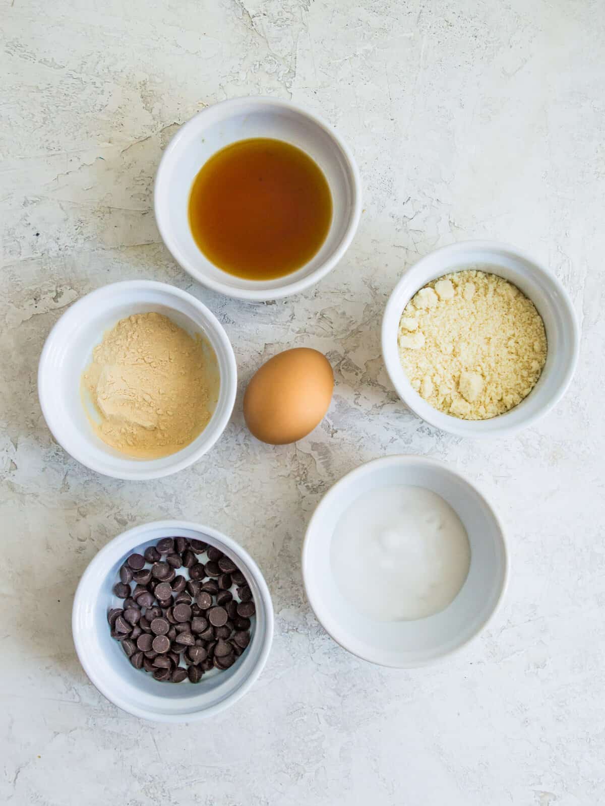 The ingredients needed to make a vanilla protein mug cake separated into small bowls.