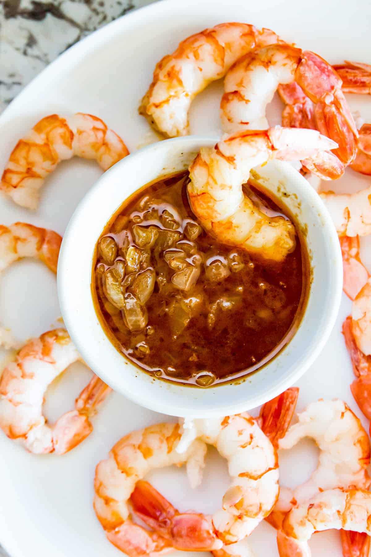 A small bowl with a cajun sauce in it with a piece of shrimp being dipped into the sauce.