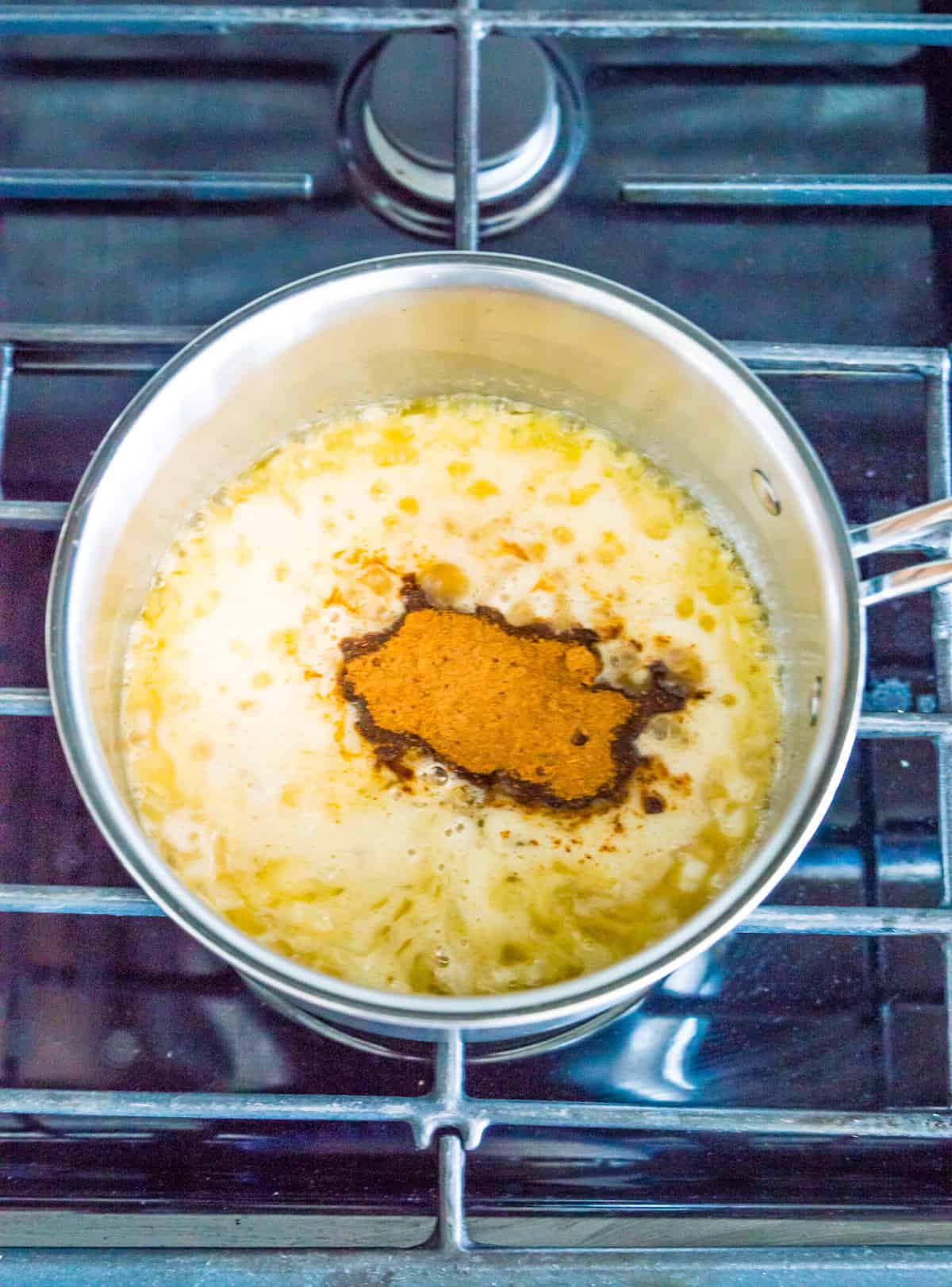 A pot on the stovetop with melted butter and seasonings simmering in it.