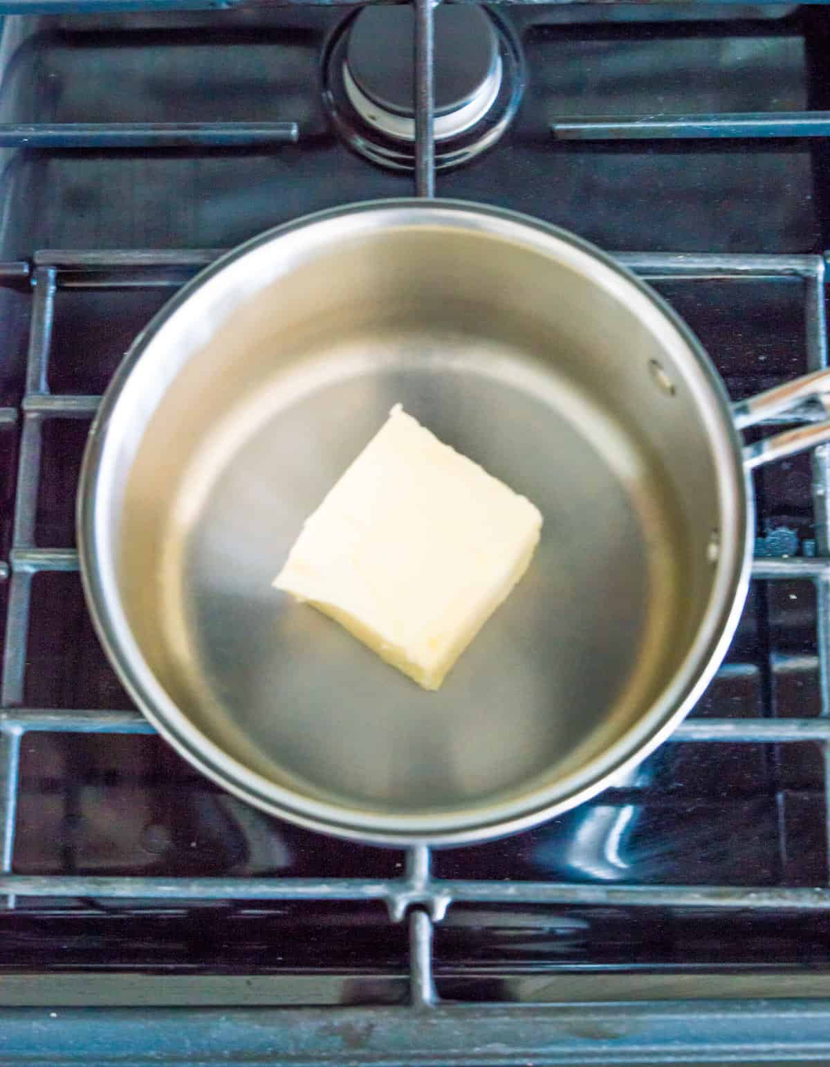 A pot on the stovetop with a stick of butter melting in it.