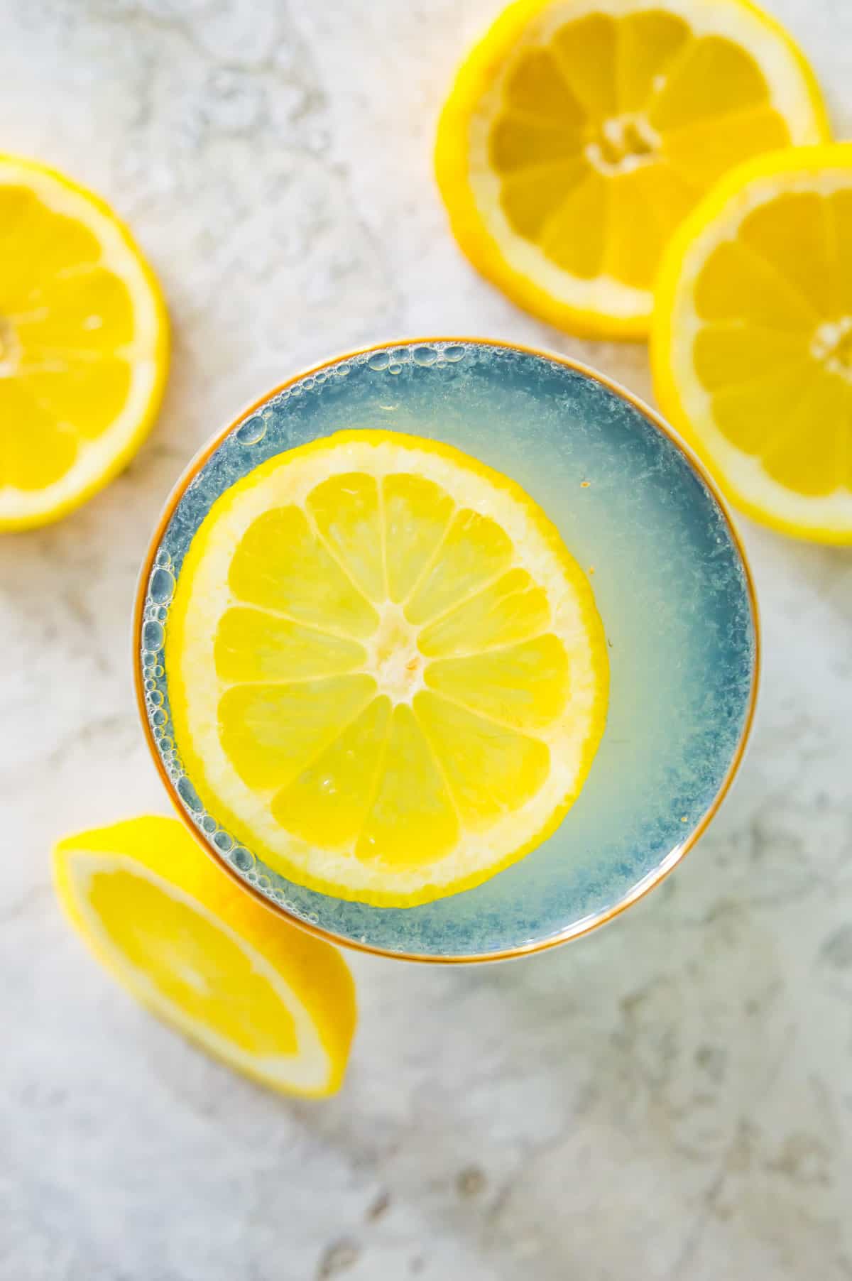 A glass of apple cider vinegar and lemon juice topped with a lemon slice.